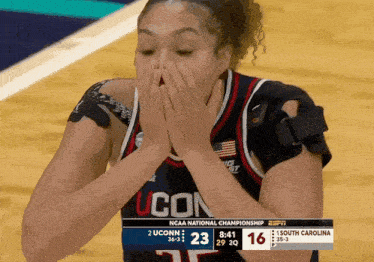 a uconn basketball player covers her mouth during a game