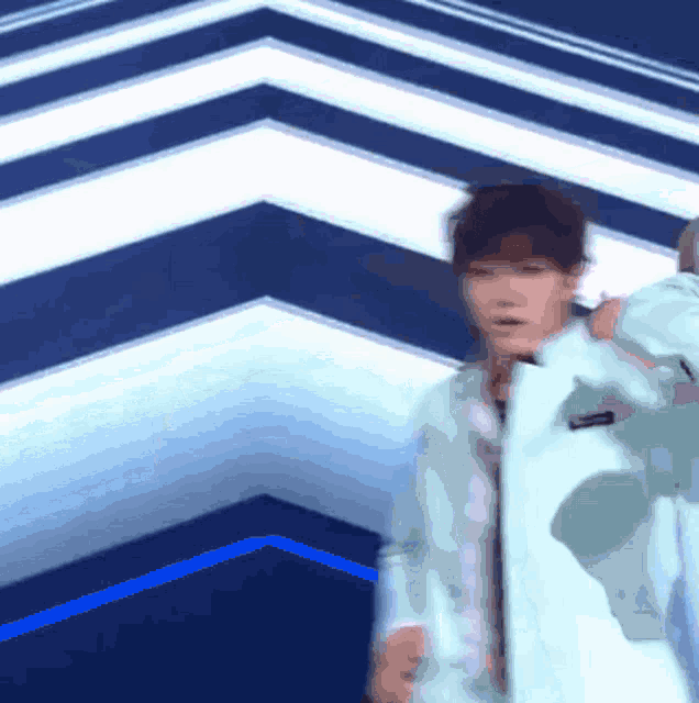a blurry picture of a person standing in a room with a blue and white striped wall