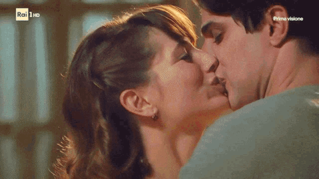 a man and a woman are kissing in front of a sign that says rai 1 hd
