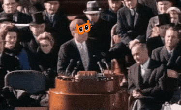 a man in a suit and tie stands at a podium with a cat on his face