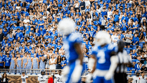 a football game is being played in front of a crowd that is wearing blue duke jerseys