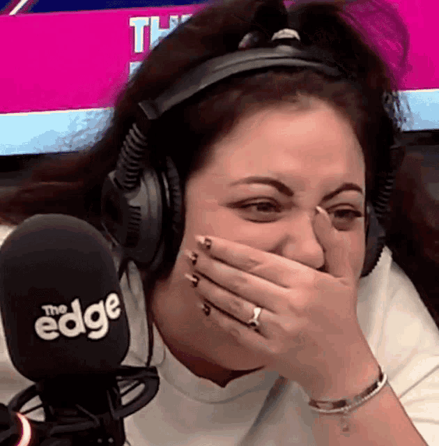 a woman wearing headphones covering her mouth with her hand in front of a microphone that says the edge