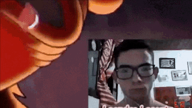 a man wearing glasses is looking at the camera in front of a cartoon .