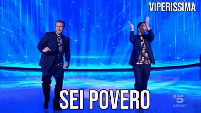 two men are dancing on a stage in front of a blue background with the words sei povero on it