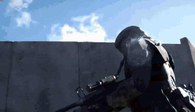 a soldier is holding a gun in front of a concrete wall