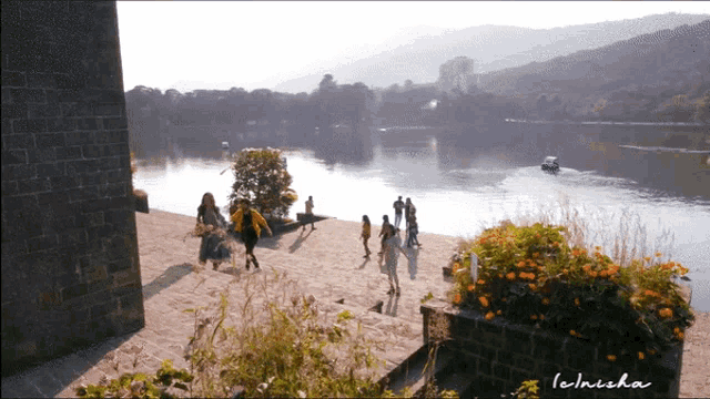 a group of people are walking along the shore of a lake with the name lemisha on the bottom right