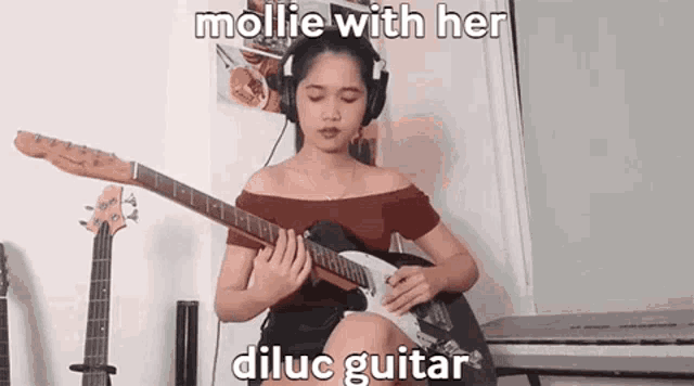 a woman is playing a guitar with headphones on .