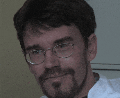 a man with glasses and a beard is smiling for the camera