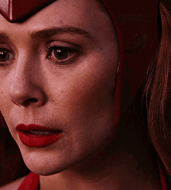 a close up of a woman 's face with red lipstick and a red helmet
