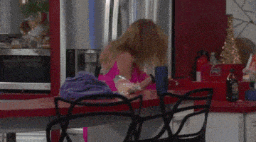 a woman in a pink dress is dancing in a kitchen with a spiral staircase .