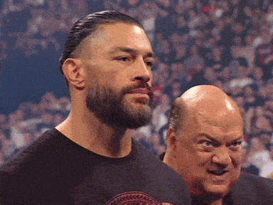 a man with a beard is standing next to a bald man in front of a crowd