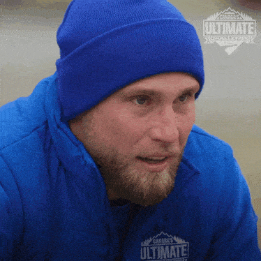 a man is wearing a blue jacket and a blue beanie that says canada 's ultimate challenge on it