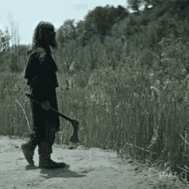 a man holding an axe in a field with starz written in the corner