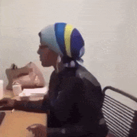 a woman wearing a striped head scarf is sitting at a table