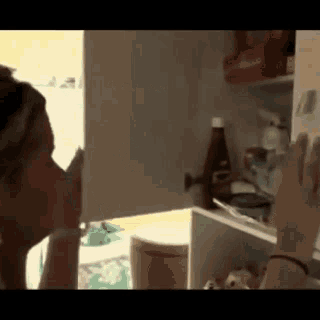 a woman is looking into a fridge with a bottle of coca cola in it .