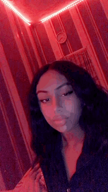 a young woman is taking a selfie in a room with red lights on the ceiling .