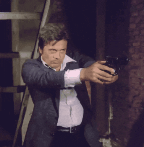 a man in a blue suit and white shirt is standing in front of a brick wall