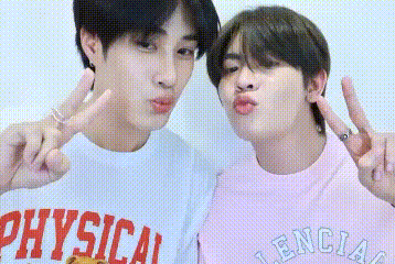two young men are standing next to each other and making funny faces while giving peace signs .