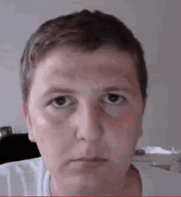 a close up of a man 's face with blue eyes and a white shirt