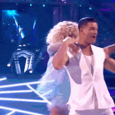a man and a woman are dancing on a stage with the number 17 behind them