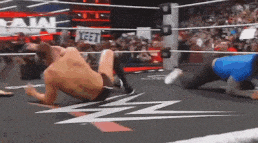 a man is wrestling another man in a wrestling ring while a crowd watches .