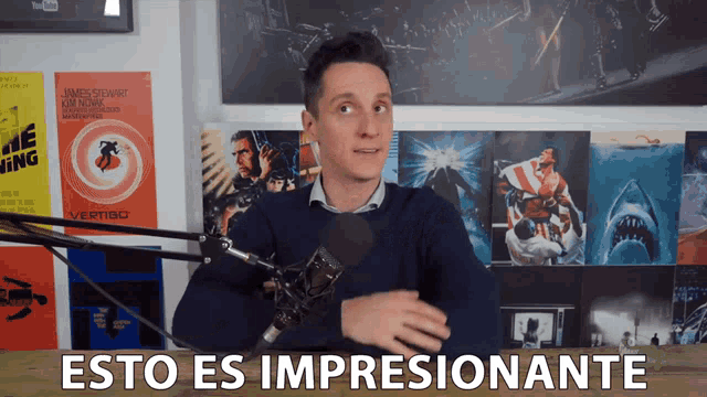 a man stands in front of a microphone with the words " esto es impresionante " below him