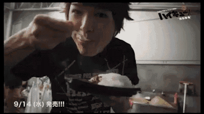 a man is eating a plate of food with a spoon in his mouth .