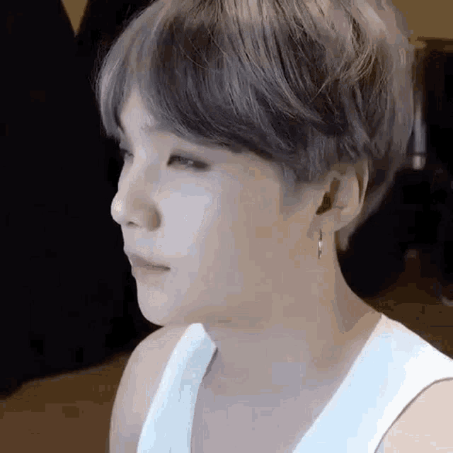 a close up of a person 's face wearing a white tank top .