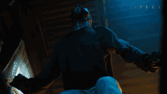 a man in a dark room with the word spell on the bottom right