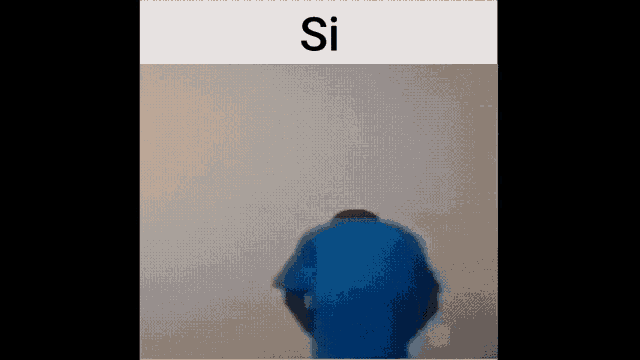 a man in a blue shirt is standing in front of a white wall with the word si on it .