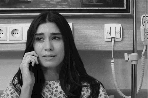 a woman in a hospital gown is crying while talking on a cell phone .