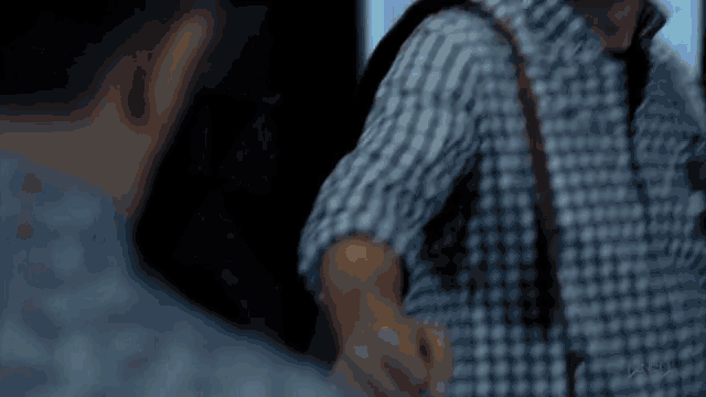 a man in a plaid shirt holds his hand up in the air