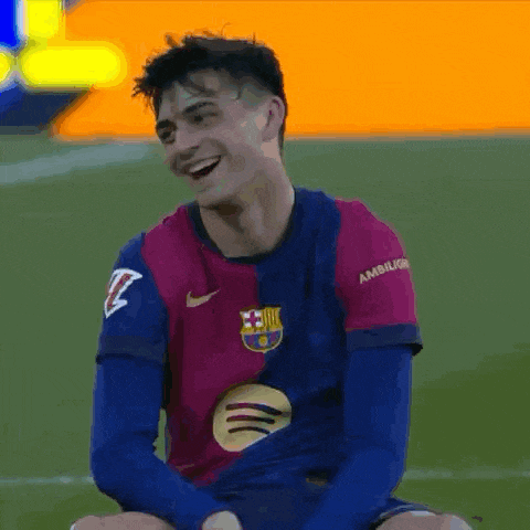 a soccer player is sitting on the field laughing and smiling .