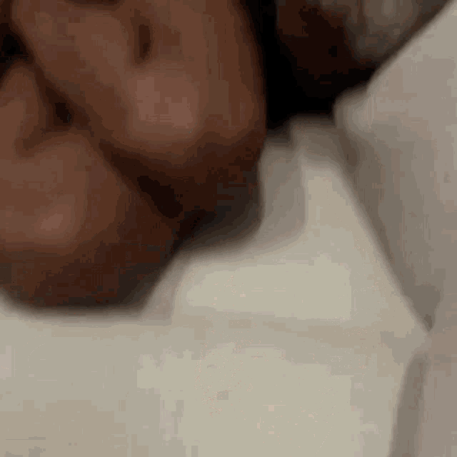 a close up of a person laying on a bed with their head on a pillow .