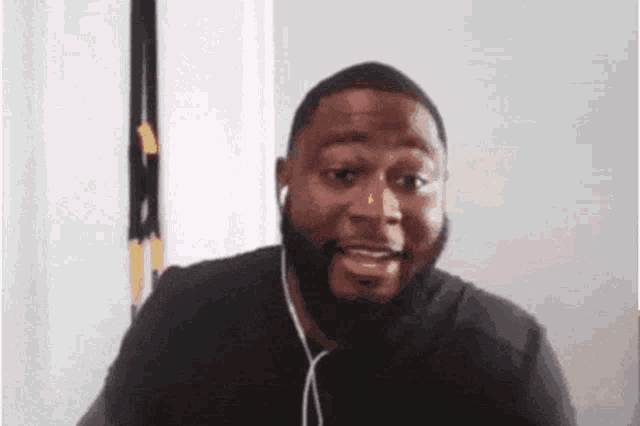 a man with a beard is wearing ear buds and smiling