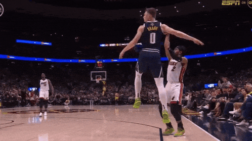 a basketball player wearing a number 0 jersey jumps over another player