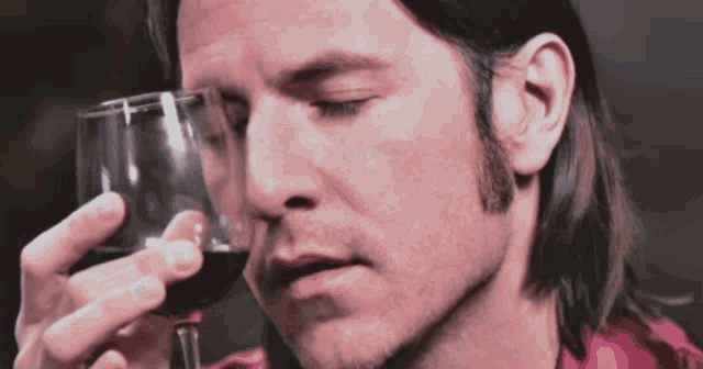 a man in a red shirt is holding a glass of wine
