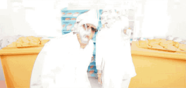 two men standing in front of a bakery counter with trays of bread