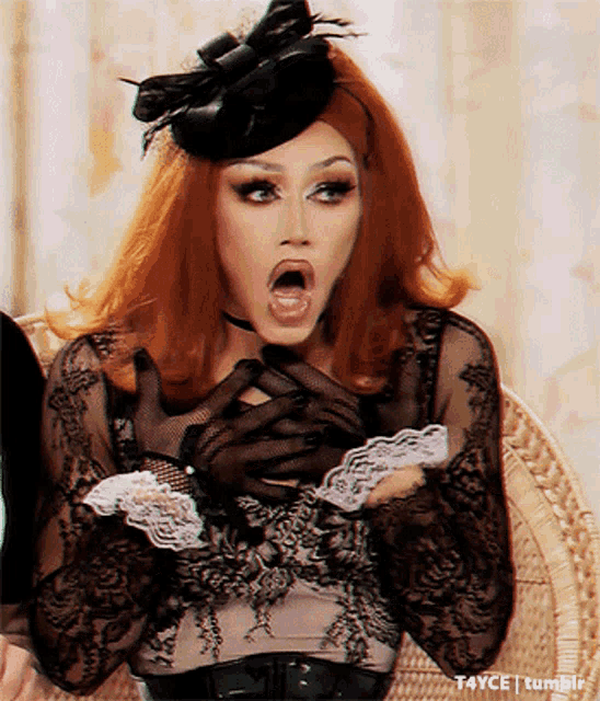 a woman with red hair is wearing a black hat and gloves and is sitting in a chair with her mouth open