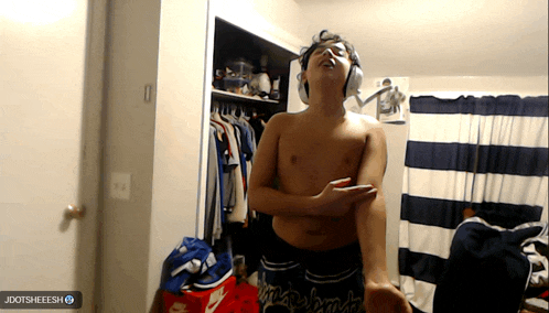 a shirtless man wearing headphones stands in front of a striped curtain and a jdotsheeesh logo