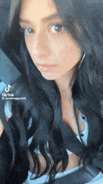a woman with long black hair is sitting in a car wearing a necklace and earrings .