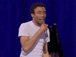 a man is singing into a microphone on a stage while holding a piece of paper .