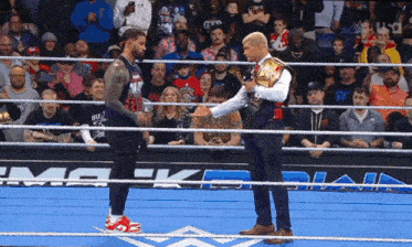 a man in a suit holds a microphone while talking to another man in a ring