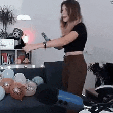 a woman is standing in front of a couch filled with balloons and holding a bottle of champagne .