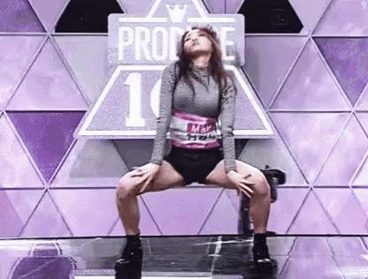 a woman is kneeling on a bench on a stage .