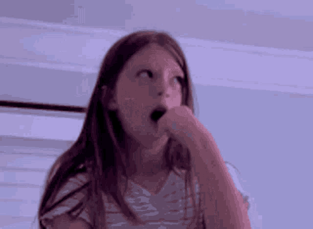 a young girl is making a funny face with her mouth open .