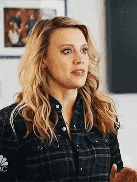 a woman in a plaid shirt is making a funny face while talking to someone .
