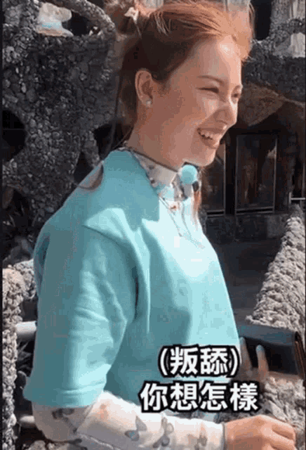a woman wearing a blue shirt is smiling in front of a rock wall