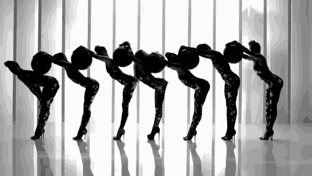 a group of women in high heels are dancing in front of a white wall