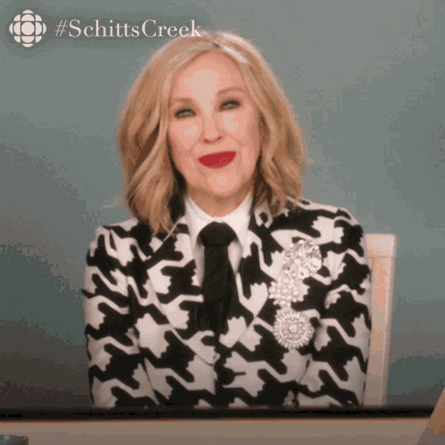 a woman is wearing a black and white suit and tie and a #schitts creek logo